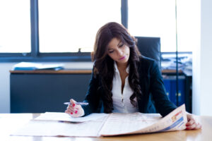 young real estate agent reads newspaper on her desk