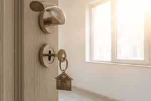 Open door to a new home with key and home shaped keychain.