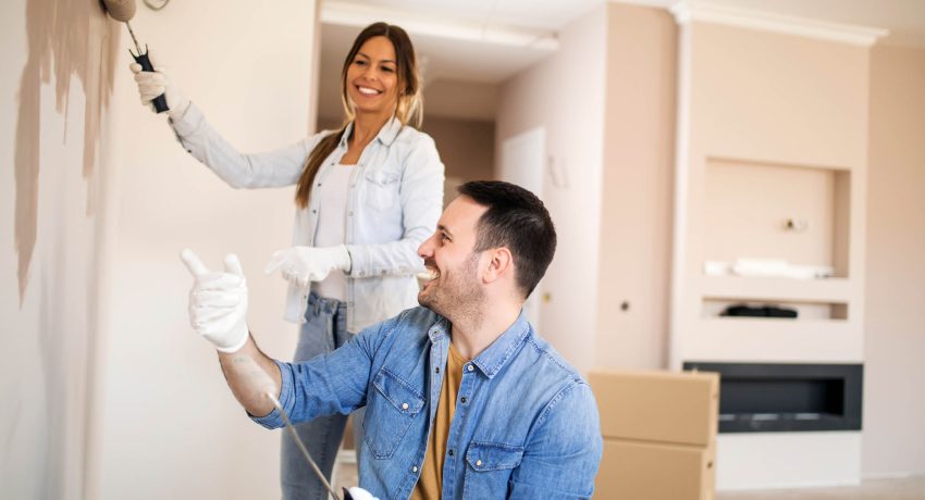 Couple painting a wall and smiling