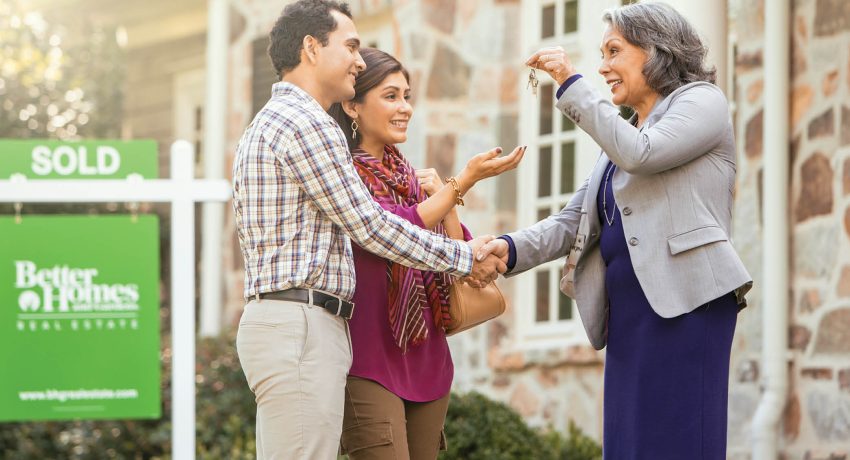 Agent giving the keys of their new house to happy couple