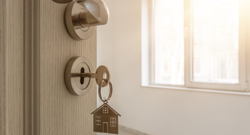 Open door to a new home with key and home shaped keychain.