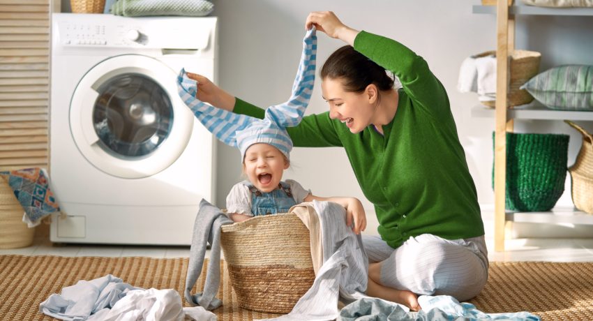 mother and daughter in laundry room playing in hamper